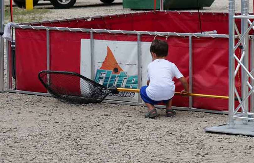 A small child with a fishing net by a Redfish Holding Tank.